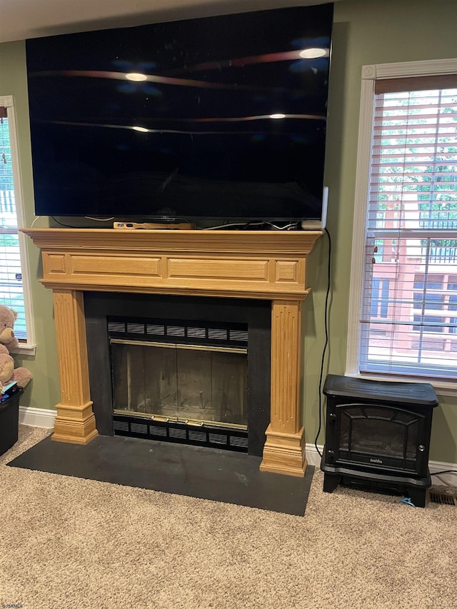 detailed view of carpet, baseboards, decorative columns, and a fireplace with flush hearth