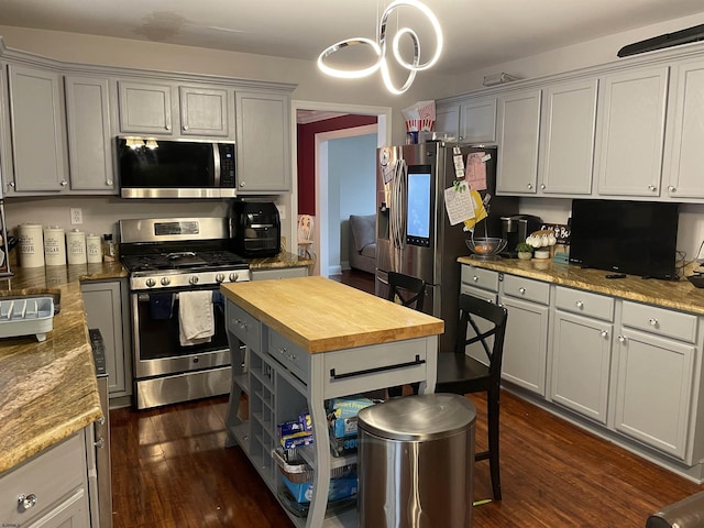 kitchen with stainless steel appliances, wood counters, dark wood-style floors, and gray cabinetry