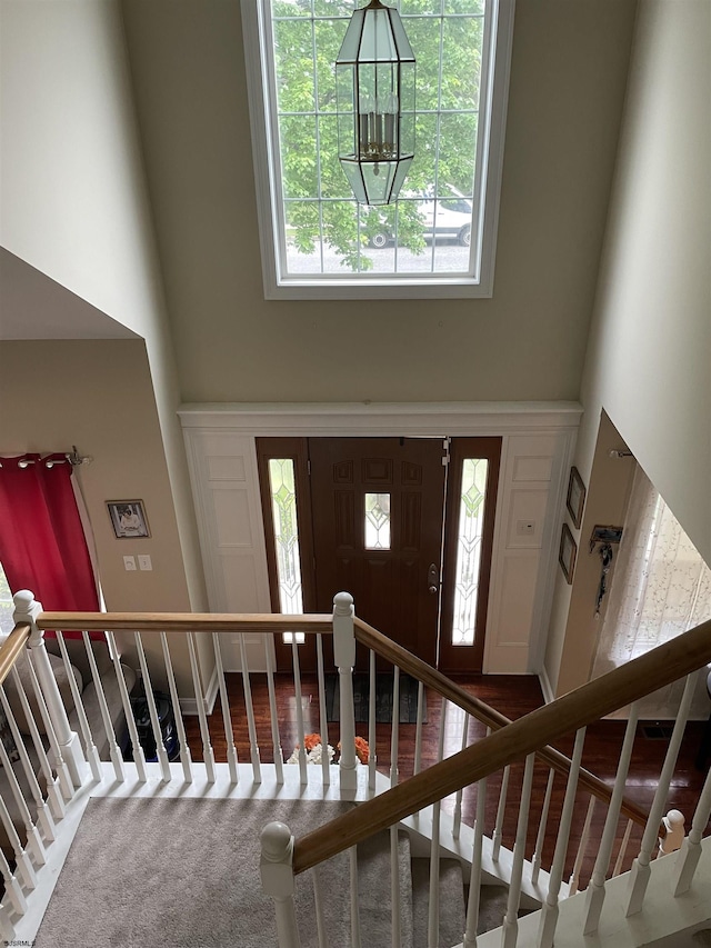carpeted foyer featuring a high ceiling and stairway