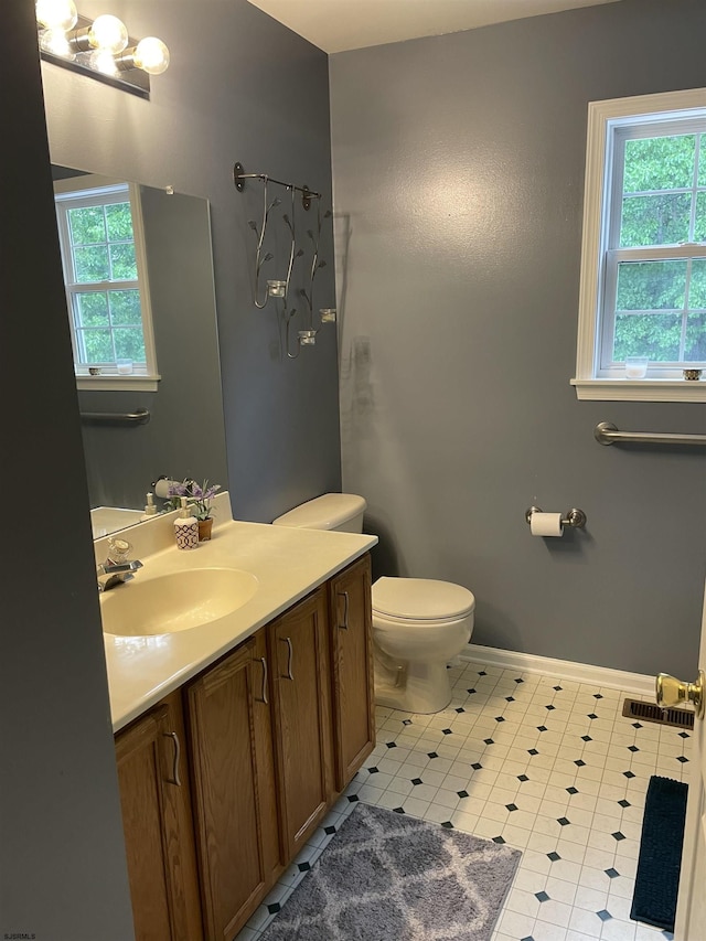 bathroom with toilet, vanity, and baseboards