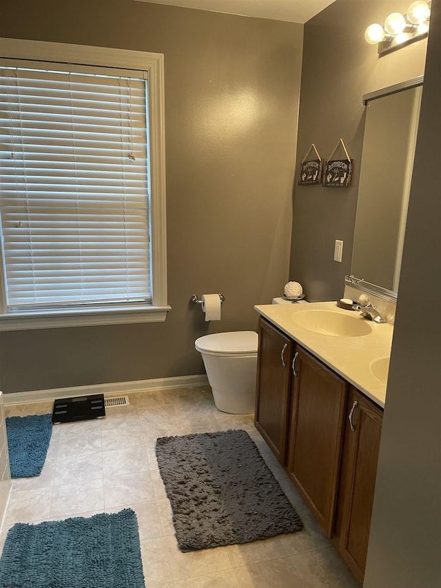 full bath with baseboards, toilet, double vanity, and tile patterned floors
