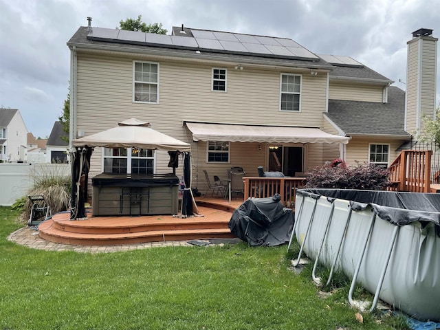 back of house featuring a covered pool, a deck, a hot tub, a gazebo, and solar panels