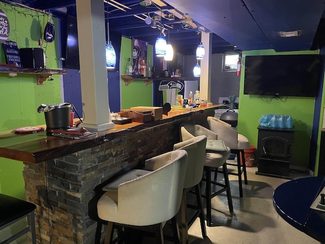 indoor dry bar featuring concrete floors and a wood stove