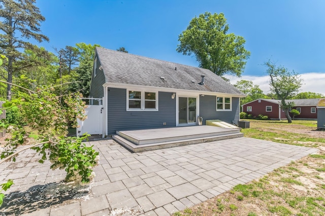 back of property with a patio area, a deck, central AC, and roof with shingles