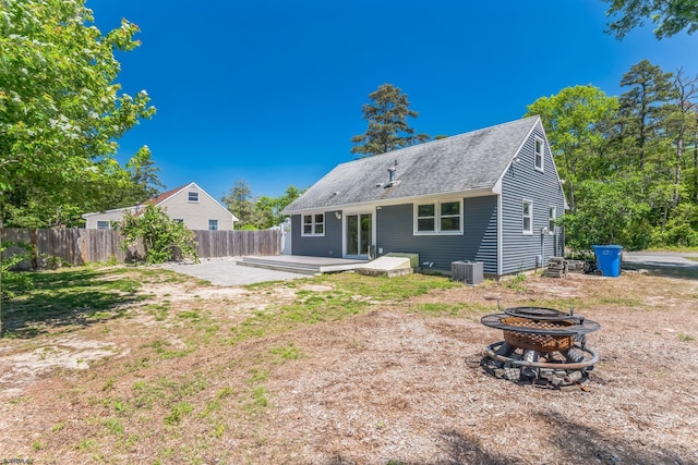 rear view of property featuring a fire pit, fence, a patio, cooling unit, and a shingled roof