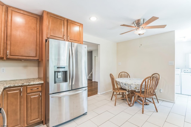 kitchen featuring stainless steel fridge, separate washer and dryer, ceiling fan, brown cabinetry, and baseboards