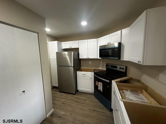 120 Heathercroft Unit 120, Egg Harbor Township, NJ 08234 - kitchen featuring black / electric stove, freestanding refrigerator, white cabinetry, dark wood-type flooring, and recessed lighting