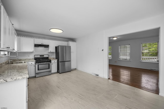 414A Upas Ave, Galloway Township, NJ 08205 - kitchen with stainless steel appliances, under cabinet range hood, a sink, white cabinetry, and decorative backsplash