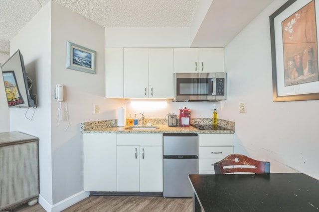 1515 Boardwalk Unit 1004, Atlantic City, NJ 08401 - kitchen featuring stainless steel appliances, a sink, wood finished floors, a textured ceiling, and light stone counters