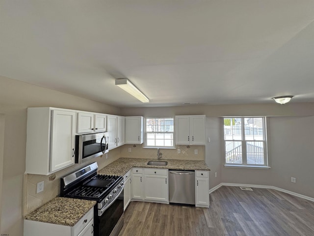 7 Nevis Dr, Egg Harbor Township, NJ 08234 - kitchen featuring stainless steel appliances, wood finished floors, a sink, white cabinets, and light stone countertops