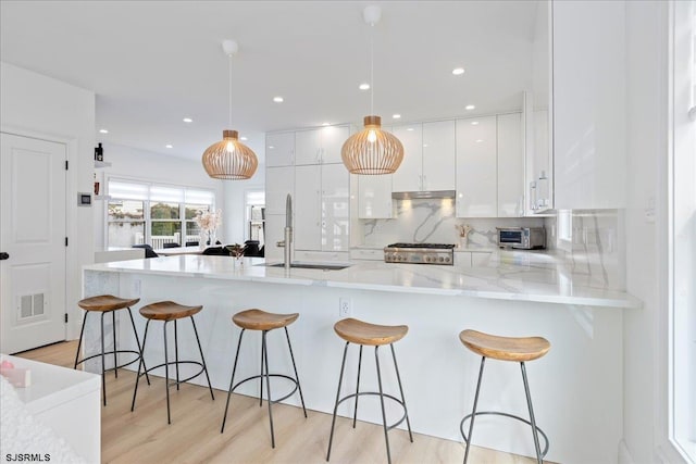 1A N Douglas Ave, Margate, NJ 08402 - kitchen featuring a sink, white cabinetry, modern cabinets, a breakfast bar area, and decorative light fixtures