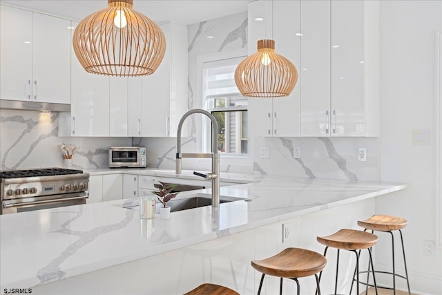 1A N Douglas Ave, Margate, NJ 08402 - kitchen with high end stove, white cabinetry, under cabinet range hood, a sink, and modern cabinets