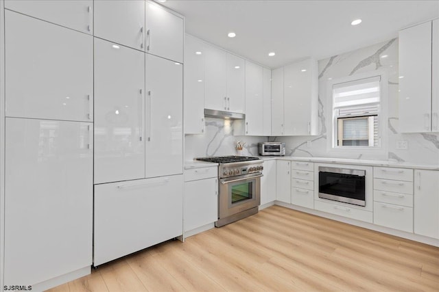 1A N Douglas Ave, Margate, NJ 08402 - kitchen with stainless steel stove, under cabinet range hood, modern cabinets, white cabinets, and light wood-style flooring