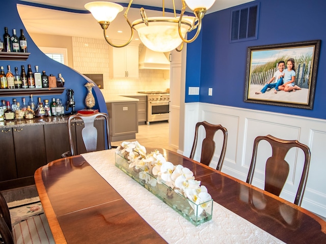 2608 Oberon Ave, Longport, NJ 08403 - dining space with a bar, a wainscoted wall, a decorative wall, and wood finished floors