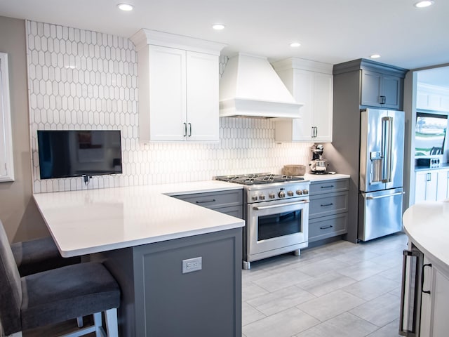 2608 Oberon Ave, Longport, NJ 08403 - kitchen featuring high end appliances, custom range hood, a breakfast bar, a peninsula, and light countertops