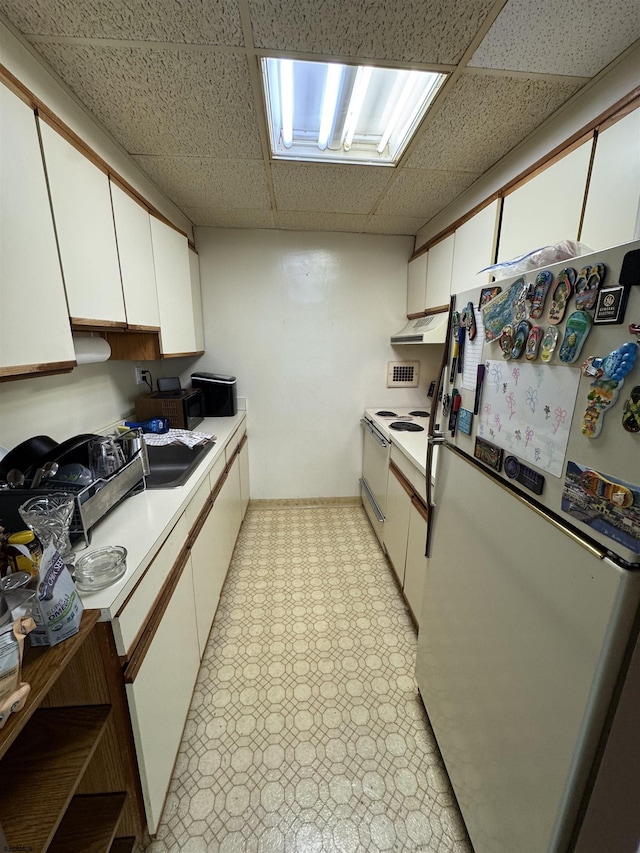 2834 Atlantic Ave Unit 401, Atlantic City, NJ 08401 - kitchen with white appliances, a paneled ceiling, white cabinetry, exhaust hood, and light countertops