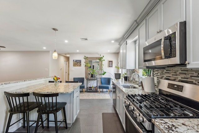 112 Drexel Ave, Egg Harbor Township, NJ 08234 - kitchen featuring stainless steel appliances, a sink, tasteful backsplash, a breakfast bar, and light stone counters