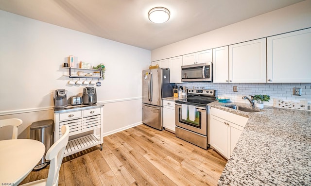 4344 W Ave Unit 26, Ocean City, NJ 08226 - kitchen featuring appliances with stainless steel finishes, a sink, light wood-style flooring, backsplash, and light stone countertops