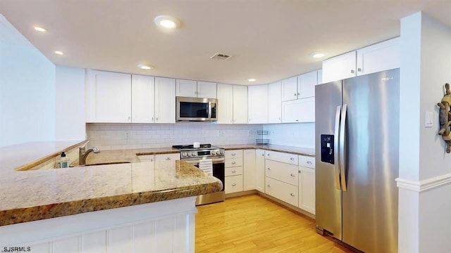 4540 W Brigantine Ave Unit N208, Brigantine, NJ 08203 - kitchen with stainless steel appliances, a sink, light wood-style flooring, decorative backsplash, and white cabinetry