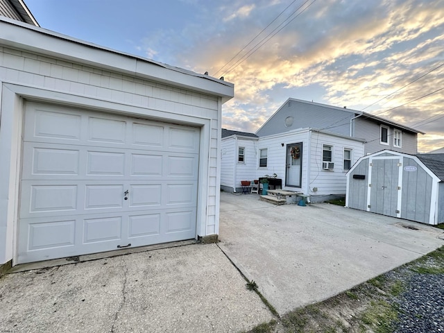 251 38th St, Brigantine, NJ 08203 - garage at dusk with a storage unit, concrete driveway, and cooling unit