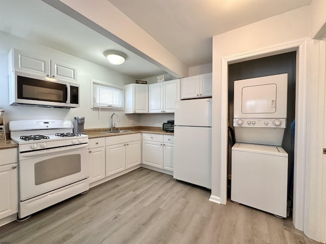 251 38th St, Brigantine, NJ 08203 - kitchen featuring white appliances, stacked washer / drying machine, a sink, light wood finished floors, and white cabinets
