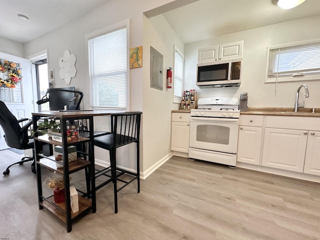 251 38th St, Brigantine, NJ 08203 - kitchen with white range with gas stovetop, a sink, healthy amount of natural light, and white cabinetry