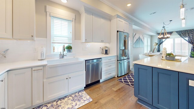 305 15th St, Ocean City, NJ 08226 - kitchen featuring stainless steel appliances, white cabinets, light wood-style flooring, crown molding, and decorative backsplash
