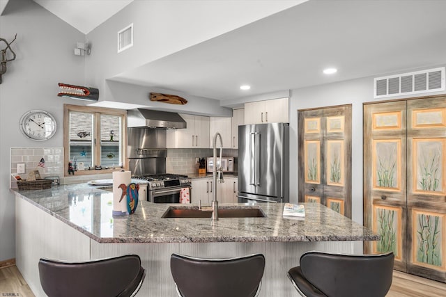 36 S Inlet Dr Unit 2, Ocean City, NJ 08226 - kitchen featuring stainless steel appliances, wall chimney exhaust hood, a peninsula, a kitchen breakfast bar, and backsplash