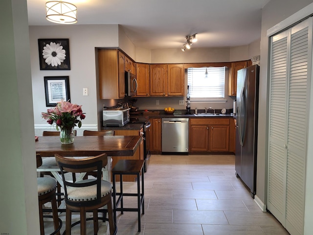 709 E Cooper Ferry Ct Unit 709, Galloway Township, NJ 08205 - kitchen featuring appliances with stainless steel finishes, brown cabinetry, a sink, dark countertops, and baseboards
