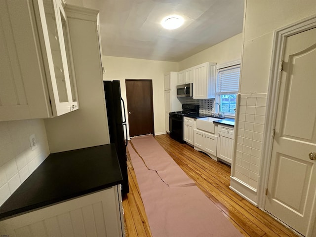 220 Seaside Ave, Atlantic City, NJ 08401 - kitchen featuring black appliances, a sink, decorative backsplash, wood finished floors, and white cabinetry