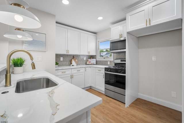 118 Colwick Dr, Somers Point, NJ 08244 - kitchen with appliances with stainless steel finishes, a sink, tasteful backsplash, light wood-style floors, and white cabinetry
