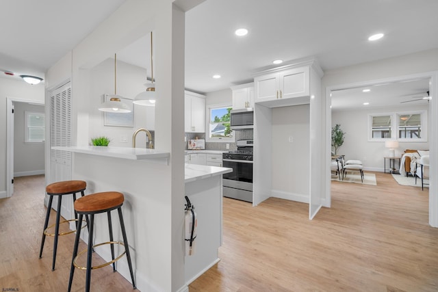 118 Colwick Dr, Somers Point, NJ 08244 - kitchen featuring stainless steel appliances, white cabinetry, a breakfast bar area, tasteful backsplash, and light wood-type flooring
