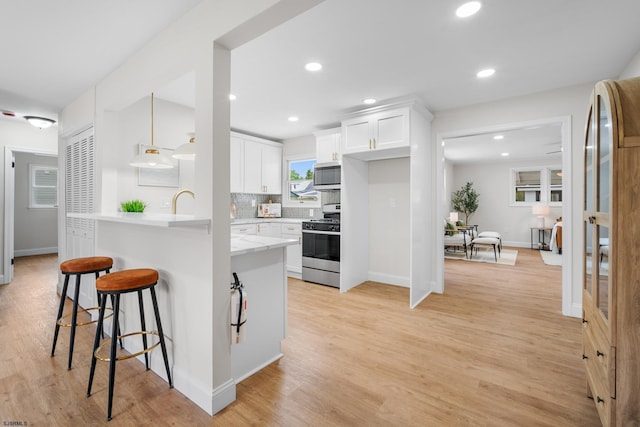 118 Colwick Dr, Somers Point, NJ 08244 - kitchen featuring appliances with stainless steel finishes, a breakfast bar, white cabinetry, light wood-type flooring, and baseboards