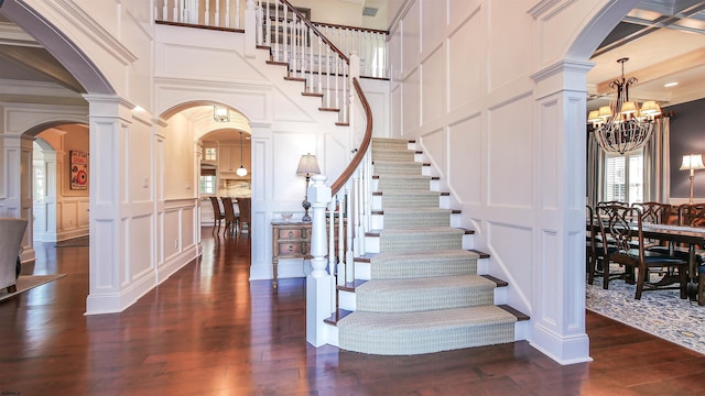 8904 Ventnor Ave, Margate, NJ 08402 - foyer entrance featuring a decorative wall, arched walkways, stairs, dark wood finished floors, and a chandelier