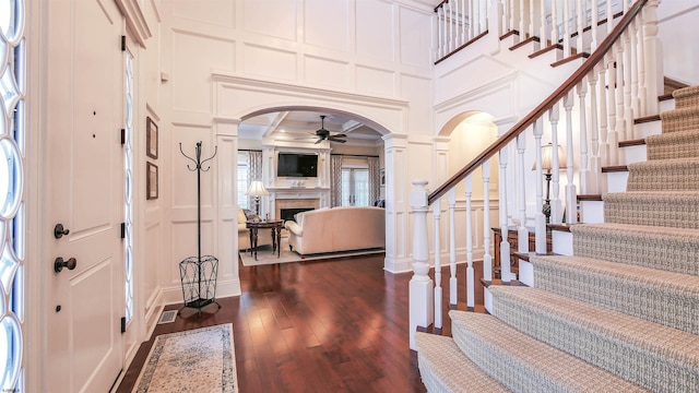 8904 Ventnor Ave, Margate, NJ 08402 - foyer entrance featuring a decorative wall, arched walkways, a ceiling fan, a fireplace, and dark wood-type flooring