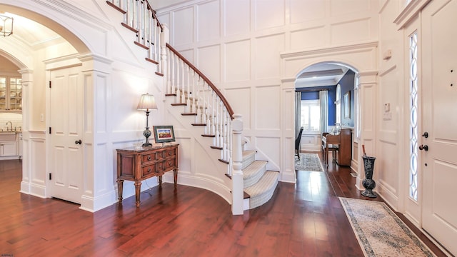 8904 Ventnor Ave, Margate, NJ 08402 - entrance foyer with a decorative wall, arched walkways, ornate columns, ornamental molding, and dark wood finished floors