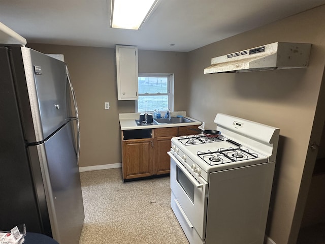 205 S Vermont Ave, Atlantic City, NJ 08401 - kitchen featuring white range with gas stovetop, freestanding refrigerator, under cabinet range hood, brown cabinetry, and light countertops
