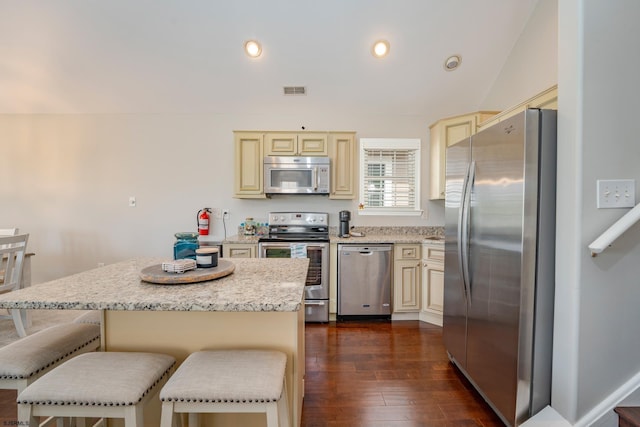 1525 Asbury Ave Unit B, Ocean City, NJ 08226 - kitchen featuring stainless steel appliances, cream cabinetry, a breakfast bar, dark wood-style flooring, and light stone counters