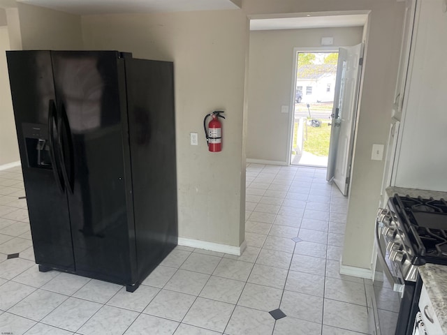 2510 Ridge Ave, Egg Harbor Township, NJ 08234 - kitchen with black fridge with ice dispenser, stainless steel range with gas stovetop, light tile patterned floors, and baseboards