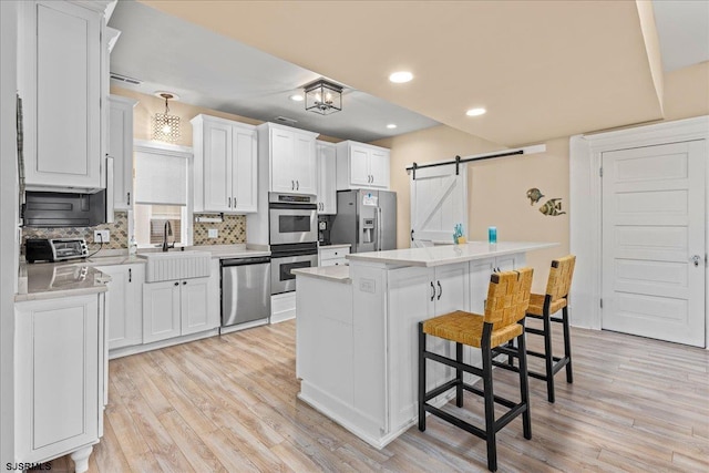 7 N Surrey Ave, Ventnor, NJ 08406 - kitchen featuring appliances with stainless steel finishes, a barn door, a sink, light wood-style flooring, and recessed lighting