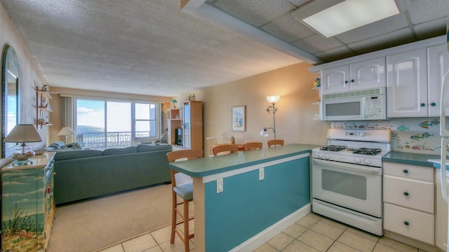 9400 Atlantic Ave Unit 305, Margate, NJ 08402 - kitchen featuring white appliances, a peninsula, a kitchen bar, white cabinetry, and open floor plan