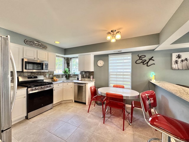 243 Churchill Dr, Egg Harbor Township, NJ 08234 - kitchen with appliances with stainless steel finishes, backsplash, a sink, light tile patterned flooring, and white cabinetry