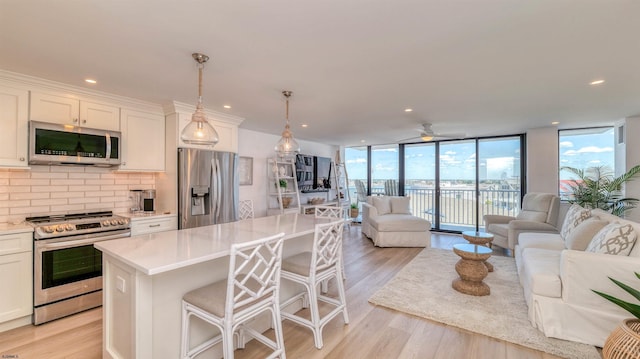 111 S 16th Ave Unit 510, Longport, NJ 08403 - kitchen with stainless steel appliances, open floor plan, a wall of windows, decorative backsplash, and light wood-type flooring