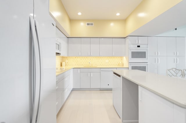 3007 Bayshore Ave Unit 23, Brigantine, NJ 08203 - kitchen featuring white appliances, a sink, white cabinets, light countertops, and backsplash