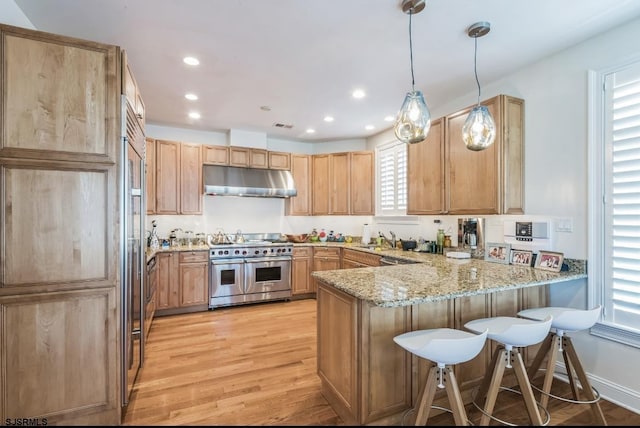3404 Ventnor Ave, Longport, NJ 08403 - kitchen with range with two ovens, under cabinet range hood, a peninsula, a sink, and light stone countertops