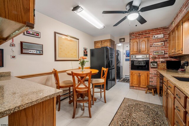 801 New York Ave, Absecon, NJ 08201 - kitchen featuring oven, black fridge, a ceiling fan, brown cabinetry, and light stone countertops