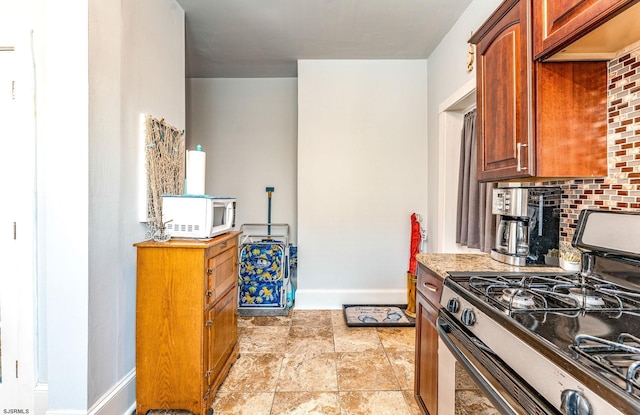 5003 Atlantic Ave Unit C04, Ventnor, NJ 08406 - kitchen featuring stainless steel range with gas cooktop, white microwave, backsplash, baseboards, and light stone finish flooring