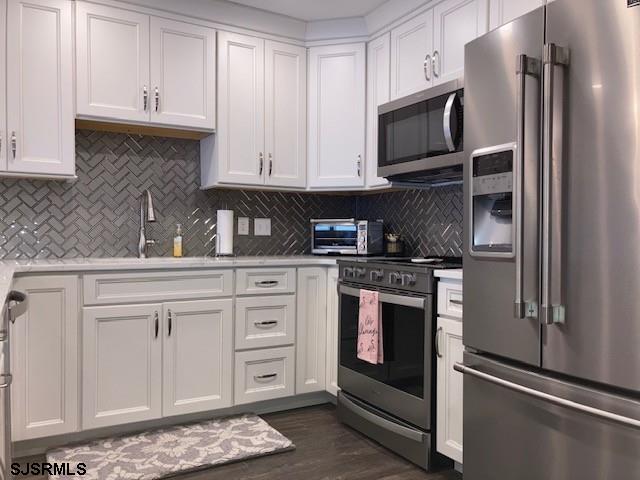 115 35th St Unit 1E, Sea Isle City, NJ 08243 - kitchen featuring appliances with stainless steel finishes, light countertops, white cabinetry, tasteful backsplash, and a sink