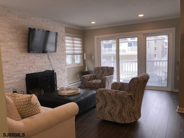 115 35th St Unit 1E, Sea Isle City, NJ 08243 - living room featuring a fireplace, baseboard heating, wood finished floors, ornamental molding, and recessed lighting