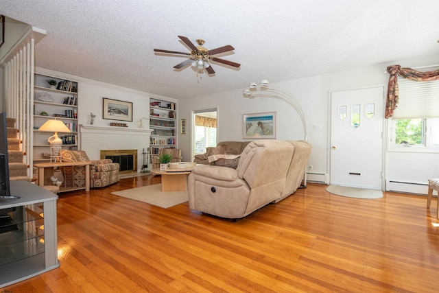 14 N Cambridge Ave, Ventnor, NJ 08406 - living room featuring a ceiling fan, light wood-type flooring, baseboard heating, a textured ceiling, and a brick fireplace